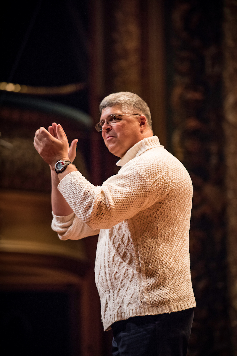 Conductor William Drury applauds from the Jordan Hall stage.