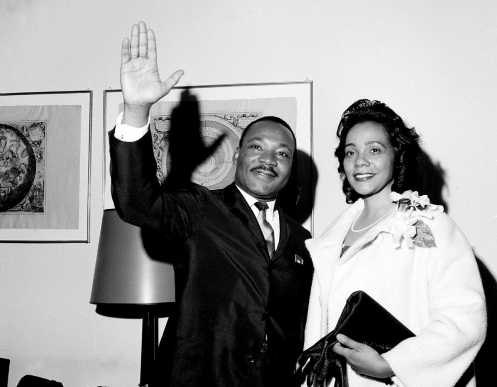 Martin Luther King smiles and waves next to Coretta Scott King, also smiling