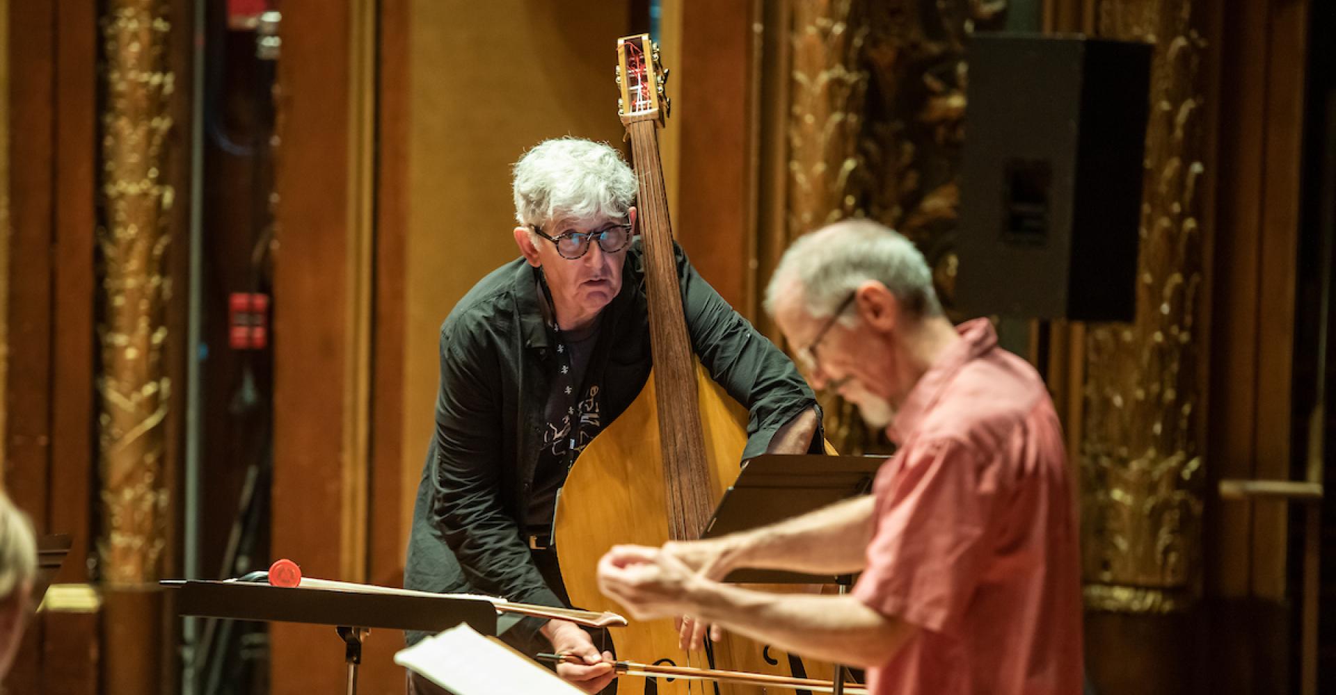 Mark Dresser plays bass and looks closely at conductor Steve Drury.