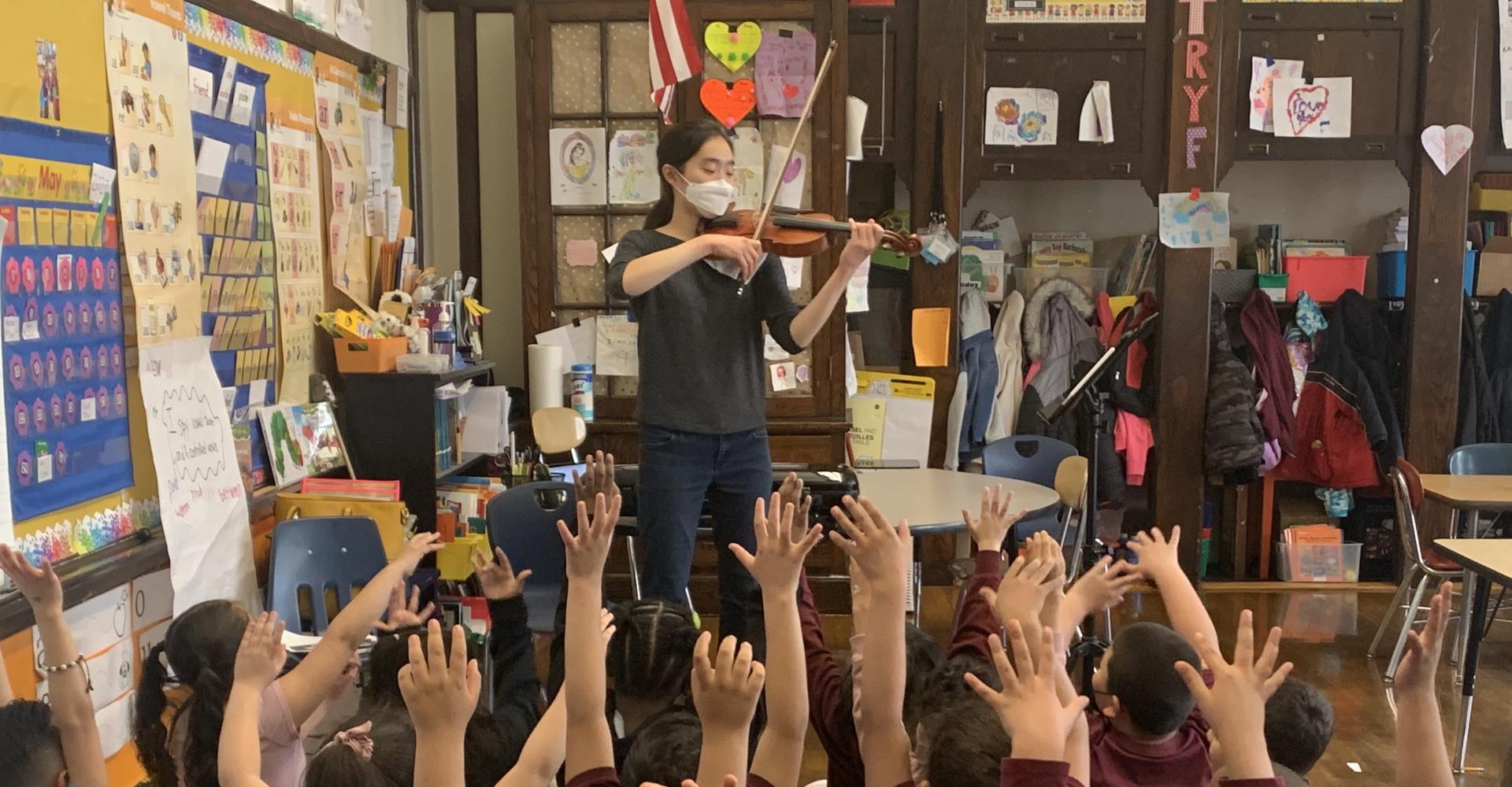Evelyn Song playing violin at a school. 