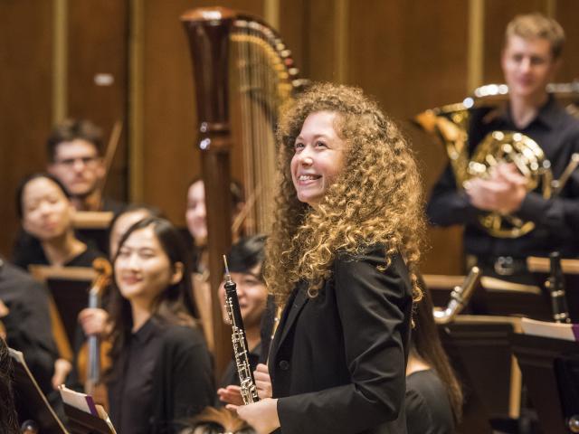 An student oboist smiles with other members of NEC Philharmonia