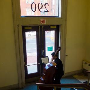 A double bassist practices in a stairwell