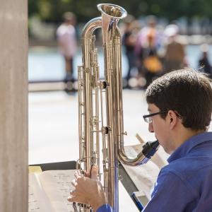 A contrabass clarinetist performs outdoors