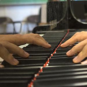 A closeup of a pianist's hands playing, with a close view of the piano keys.
