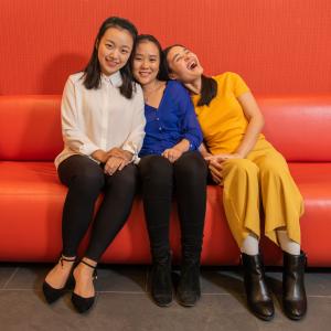 Three members of the Asian Student Association Executive Board smile and laugh while sitting on a couch.