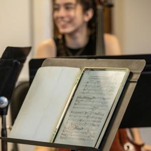In the foreground, a music stand with a handwritten Beethoven manuscript on a tablet. In the background, a member of the quartet smiling.